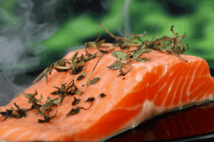 A piece of salmon with herbs on top.